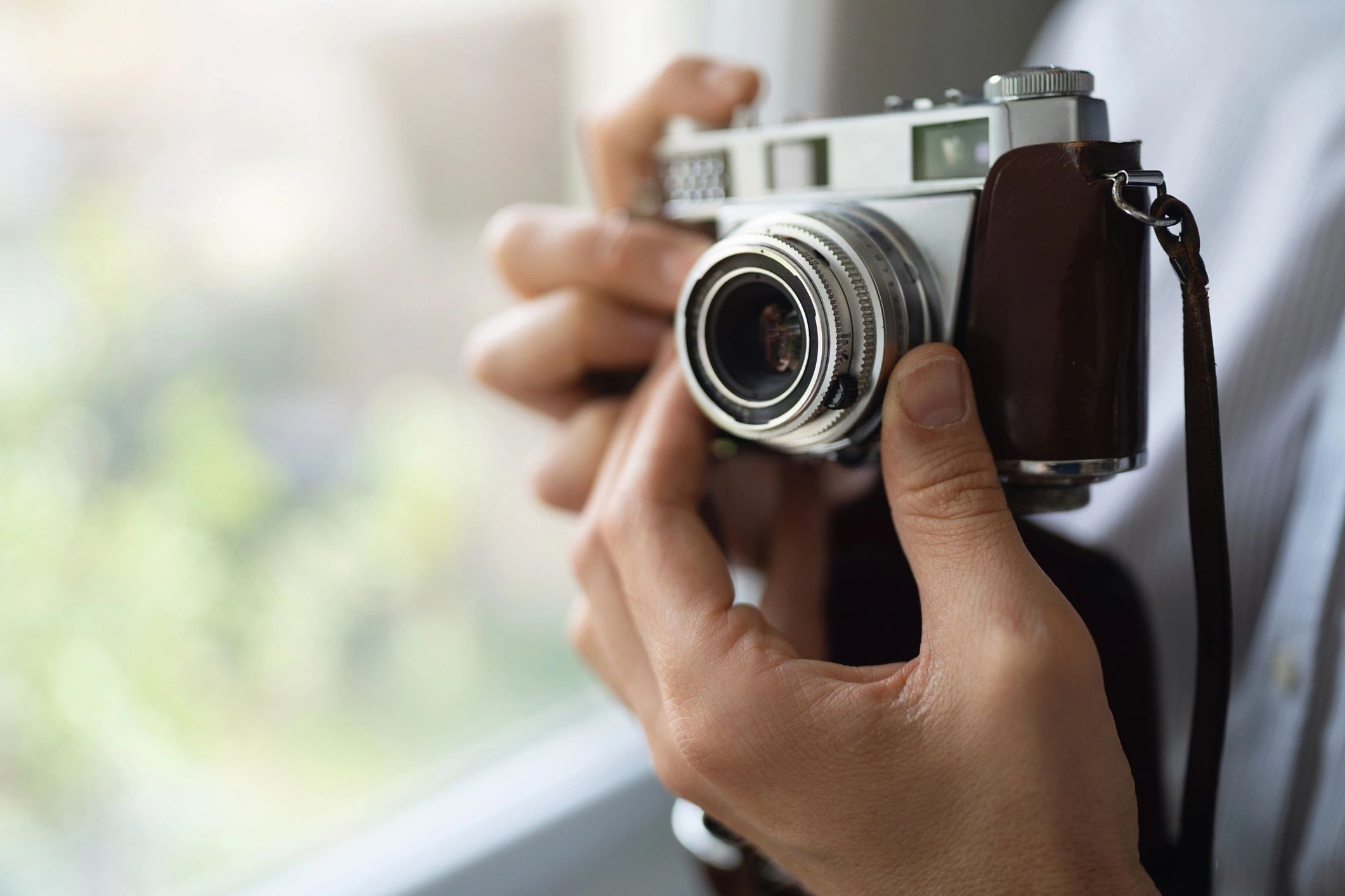 Photographer holding a camera near a bright window