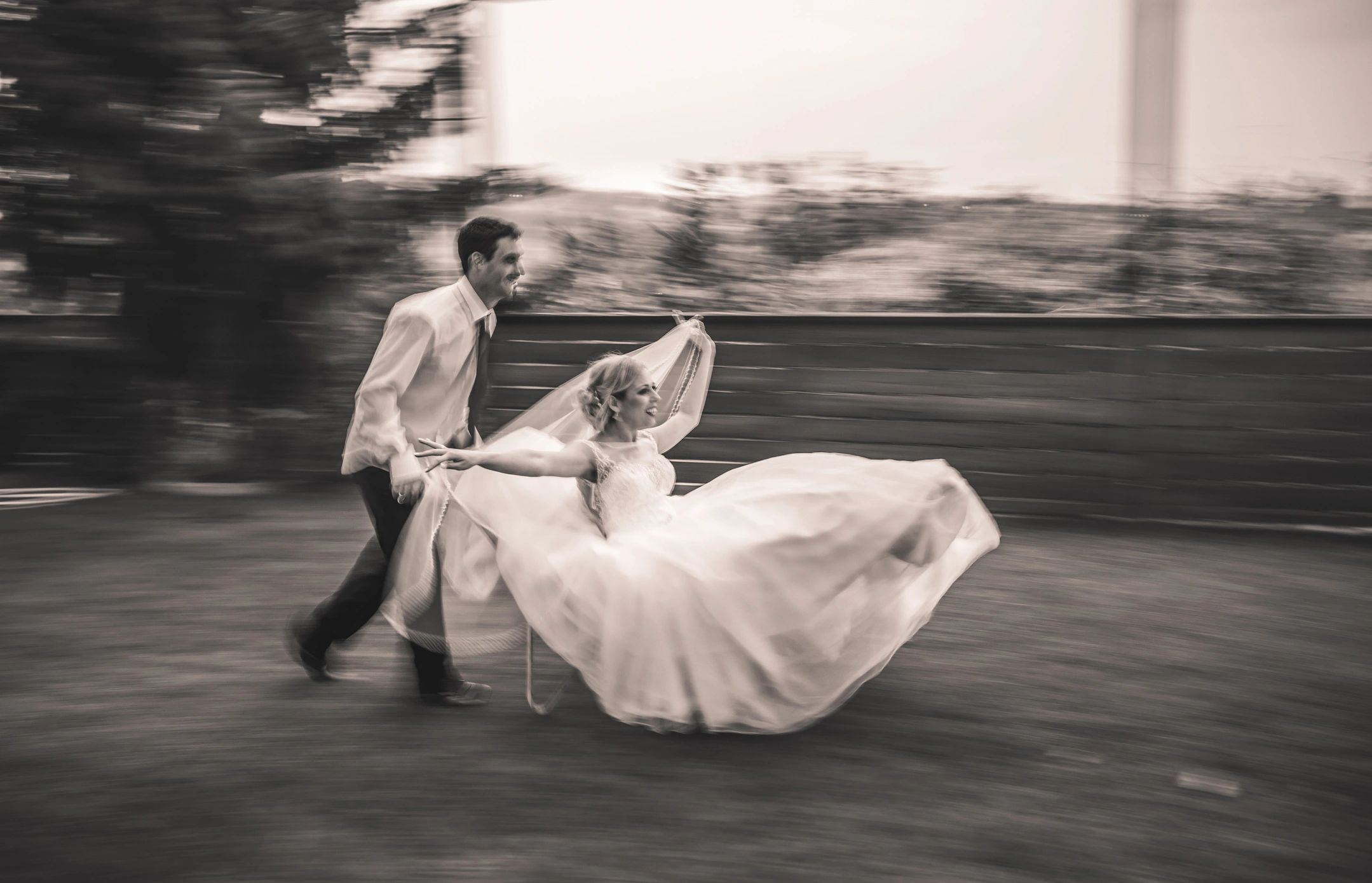 Playful newlyweds with groom pushing bride in a wheelbarrow