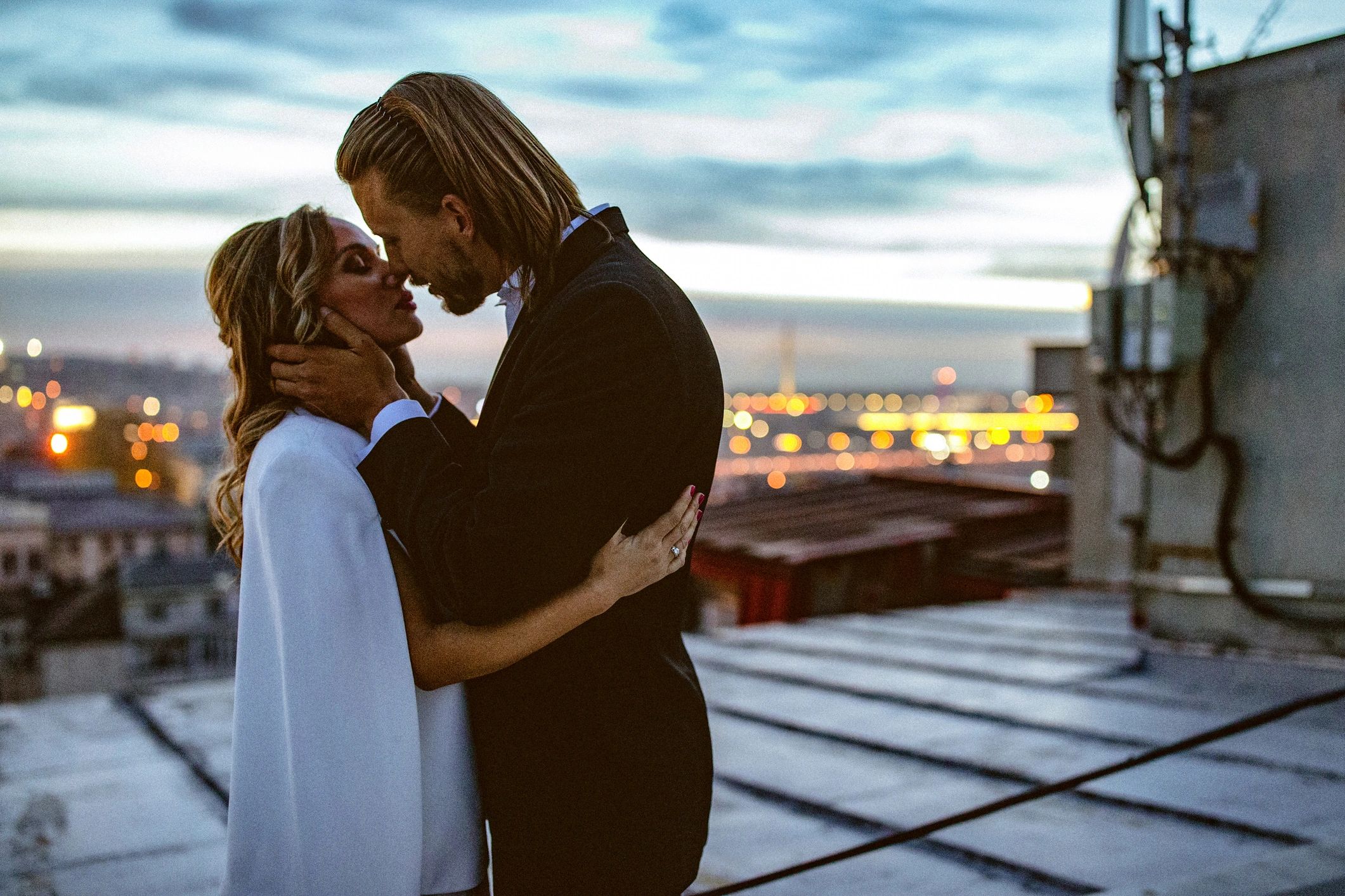 Bride and groom embracing on a rooftop at sunset